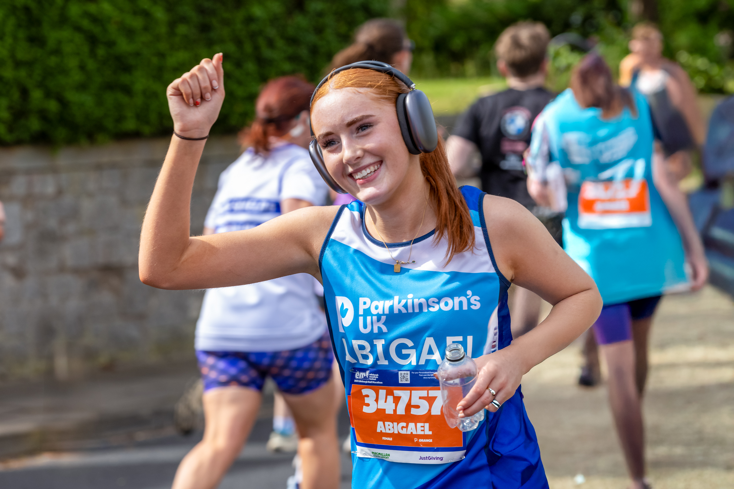 Runner in Edinburgh Marathon smiling at camera and raising arm in the air