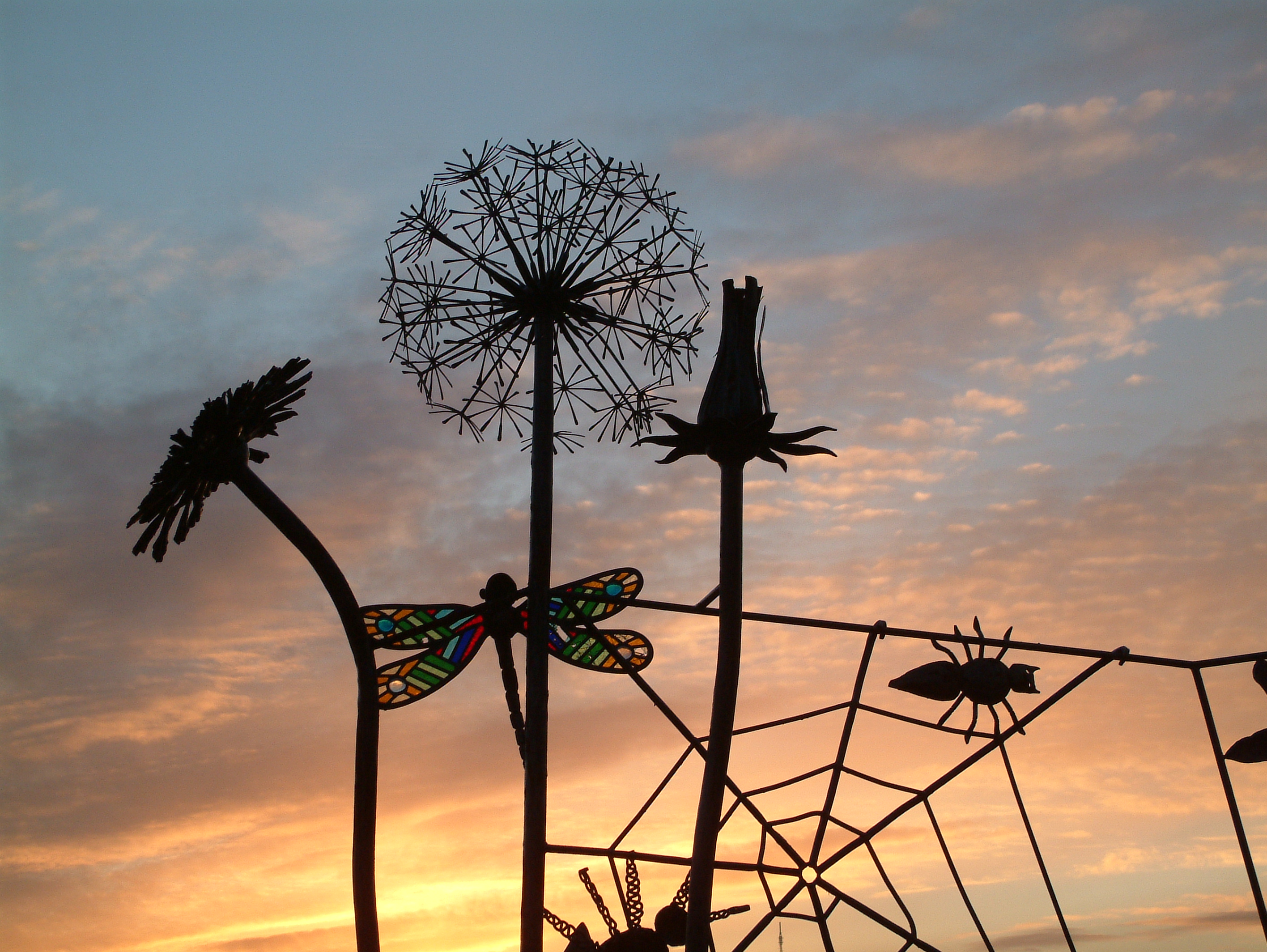 Image of sunset with decorative sculptures of flowers and insects